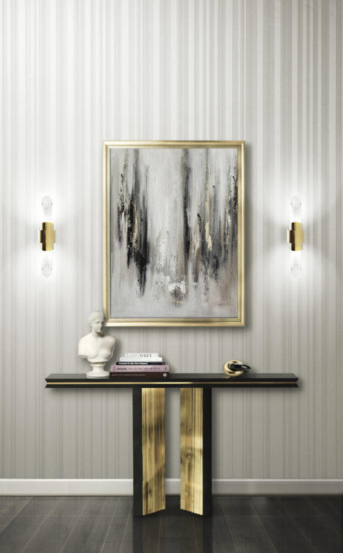 Impressionnante console dorée Beyond de Luxxu. Sur la console, un buste et quelques livres. Tableau brumeux. Les deux appliques Tycho font ressortir le revêtement mural Infinity.