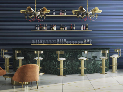 Bar en marbre vert avec tabourets de bar dorés. Deux lampes dorées accrocheuses avec des cordons électriques rouges. Verres et bouteilles derrière le bar. Revêtements muraux Infinity à rayures bleues.