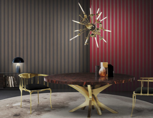 Les chaises et la table design en or sont le point de mire de cette salle à manger. Le plateau de table en marbre rouge se marie bien avec le revêtement mural à rayures rouges de la gamme Infinity.