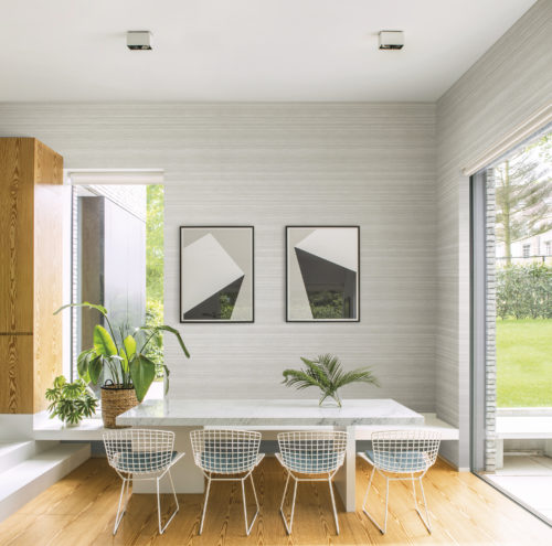 Cette magnifique image montre une salle à manger décorée avec le doux imprimé monochrome de la collection Omexco Loft. Le motif du mica imprimé invite à la contemplation.
