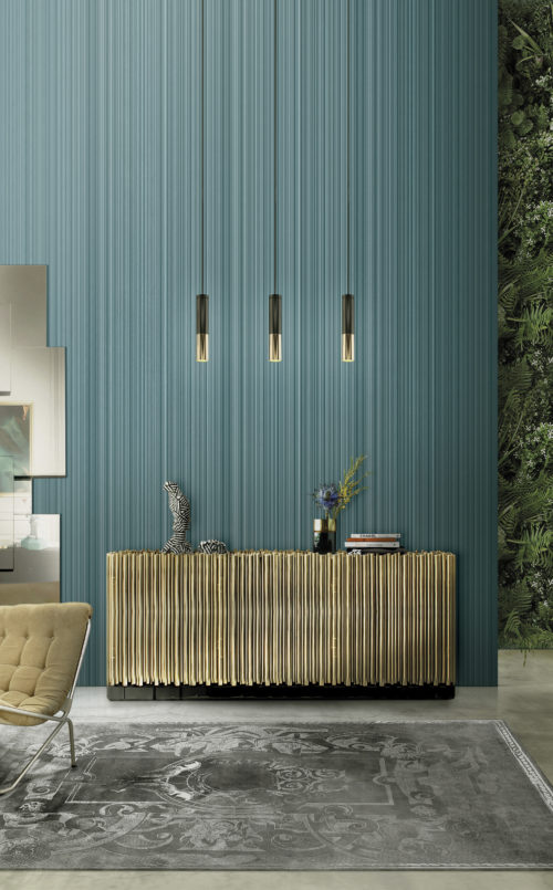 Buffet symphonique avec des tuyaux dorés. Au-dessus, 3 lampes suspendues en or et noir. Livres sur le buffet, dont un intitulé "Chanel". Impressionnant revêtement mural en faux cuir à rayures.