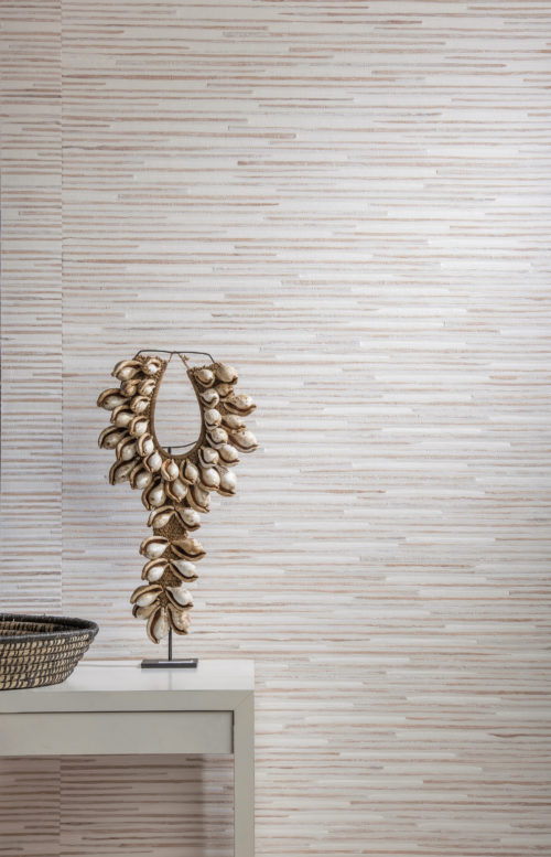 Détail d'un nénuphar et d'un revêtement mural en papier tissé dans des tons blancs et nus. Œuvre d'art avec des coquillages sur une console blanche.