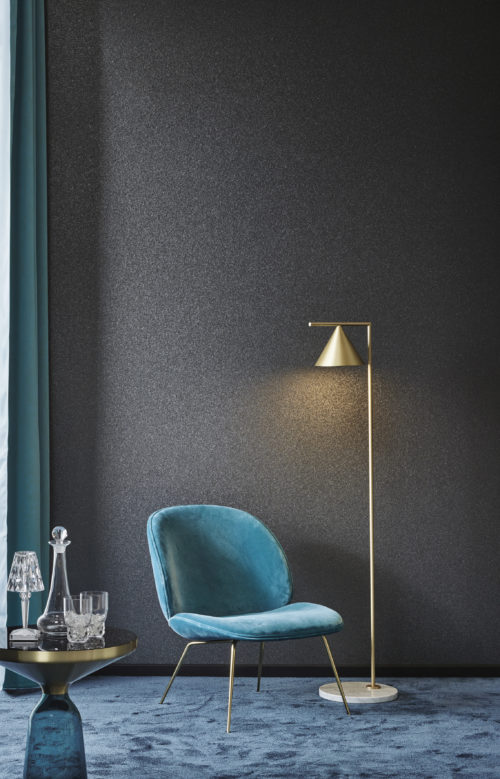 Revêtement mica gris foncé de la gamme Omexco Graphite. Chaise et rideau turquoise. Petite table ronde avec verres.