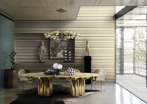 Table de salle à manger dorée avec structure en bois dans une salle à manger bien éclairée. Le revêtement mural Infinity à rayures dorées donne de la profondeur à la pièce. Œuvres d'art en noir et blanc.