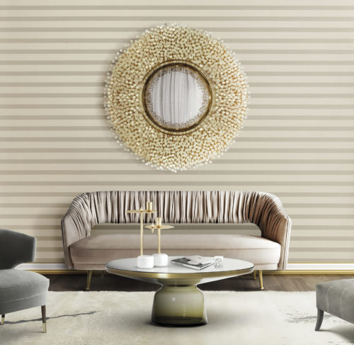 Salon clair avec canapé en velours rose. Le tissu du dossier présente de jolis plis. Au-dessus, un miroir avec des détails en nacre. Revêtement mural Infinity.