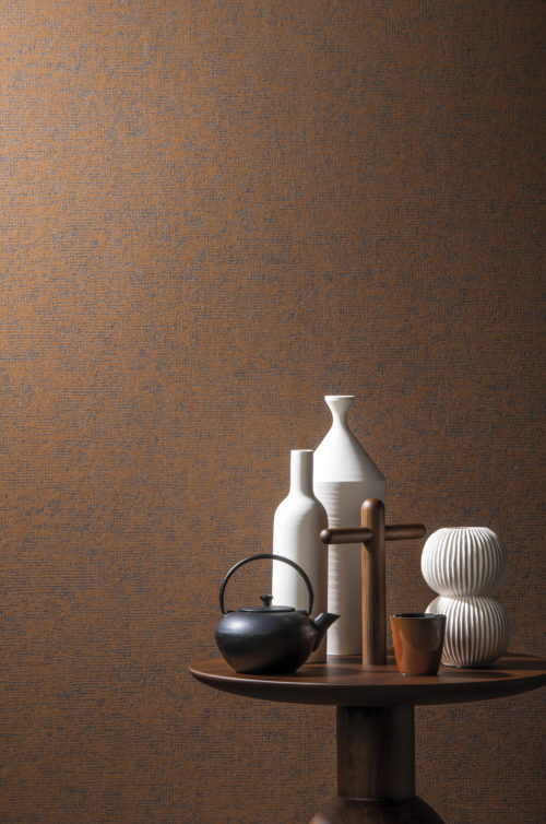 Joli contraste entre le revêtement intissé couleur rouille et les accessoires posés sur une petite table en bois avec poignée en forme de croix : des vases blanc mat, une théière japonaise.