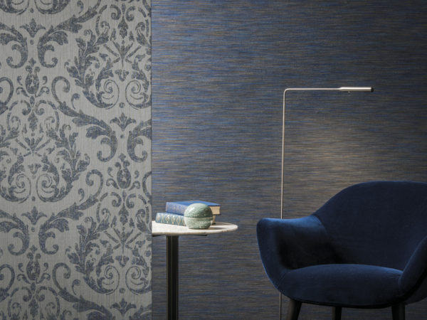 Chambre tactile avec un élégant revêtement mural en damas et un revêtement mural bleu foncé en teinture d'espace. Un siège en velours et une liseuse invitent à la détente. La collection Omexco Elegance.
