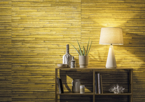 Gros plan sur un revêtement mural jaune nénuphar avec des étagères en bois. Lampe blanche, livres et fossile marin.