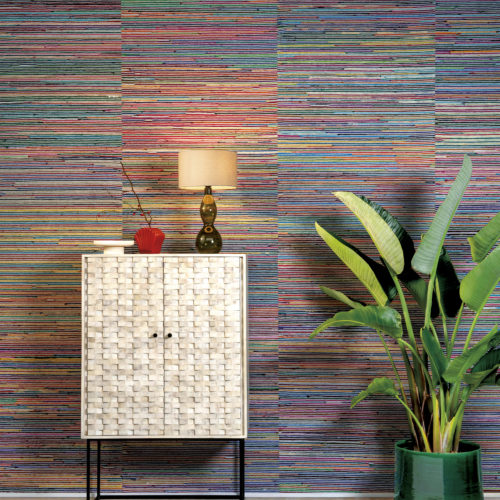 Un décor tropical avec un sol et une moquette beiges, un bananier exotique, une armoire en bois à deux portes sur un cadre métallique minimal et une lampe de table éclairée avec abat-jour. Mais ce qui attire vraiment l'attention dans cette pièce, c'est le revêtement mural extrêmement coloré de l'atelier de collection d'Omexco : de la soie de sari recyclée est torsadée en rubans et tissée à la main avec des ficelles de papier. La texture faite à la main vous remplit de joie et de beauté.