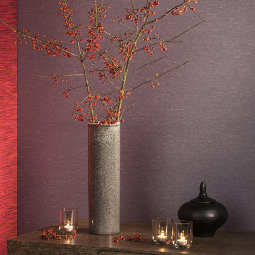 Cadre chaleureux avec un vase gris, des baies, des bougies, un revêtement mauve et rouge vif Elegance.