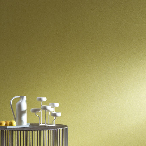 Table contemporaine en fil de fer avec vase et bougeoirs blancs. Le jaune des citrons sur la table se retrouve dans le revêtement mural jaune graphite.